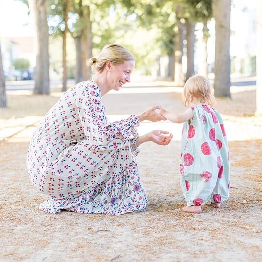Mutter sitzt auf Fußboden und hält ihr kleines Kind fest