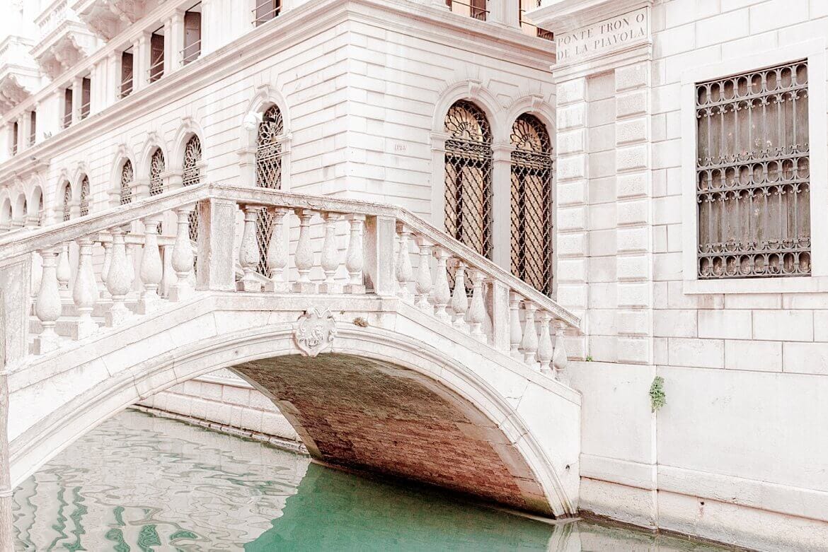 Brücke in Venedig über türkisblauen Kanal umrandet von weißen Gebäuden