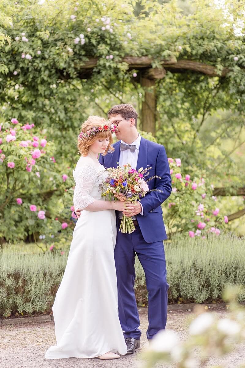 Brautpaar umringt von Rosen im Park