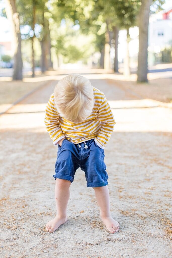 Kleiner Junge guckt an seinen Beinen herunter