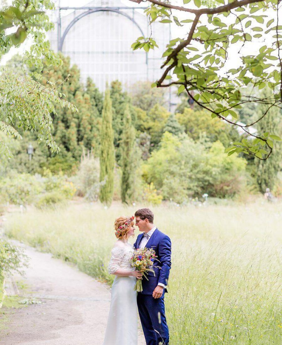 Hochzeitsfotograf Berlin Brautpaar im Park mit Gewächshaus im Hintergrund