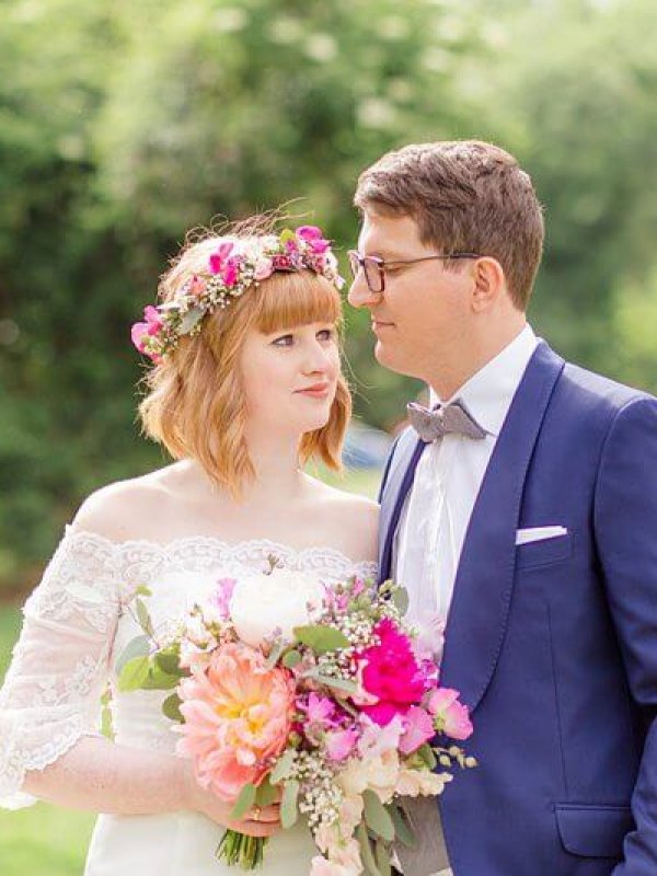 hochzeitsfotograf-berlin_kundenstimmen028 Brautpaar im Grünen mit Blumenkranz und großen pinken Blumen