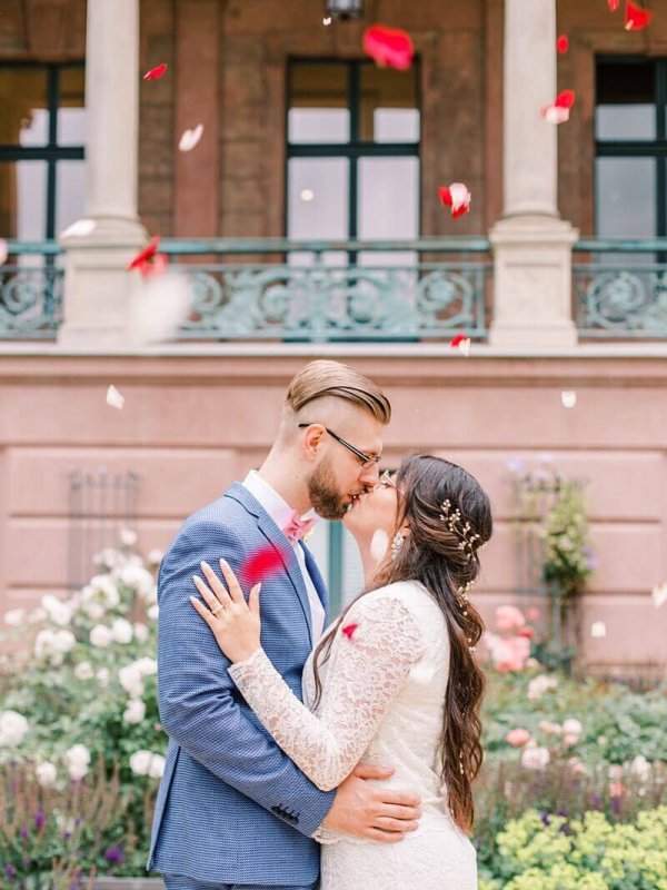 Hochzeitsfotografin Schloss Biesdorf Berlin Hochzeitspaar küsst sich unter Blütenregen