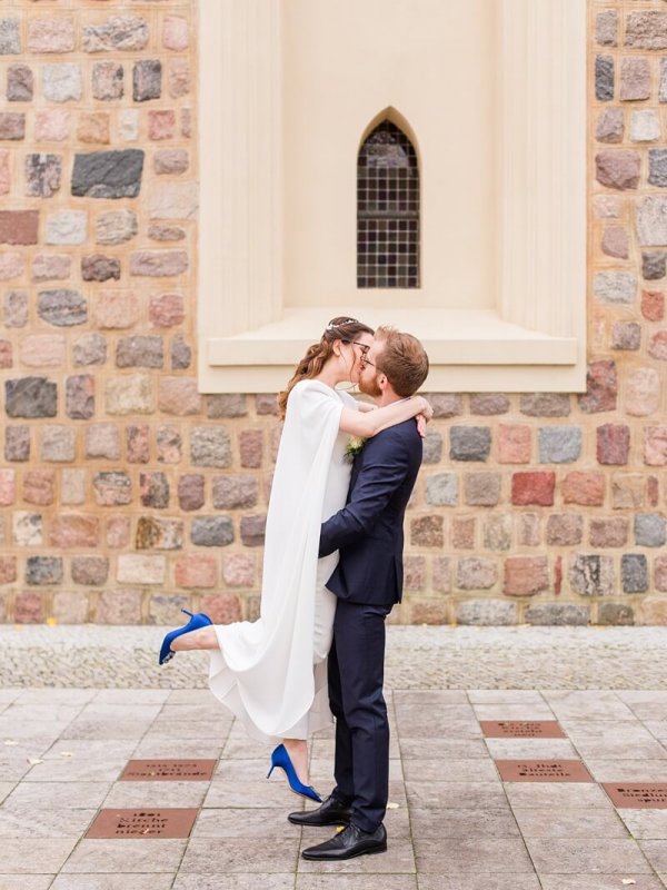 Hochzeitsfotografie Berlin Bräutigam hebt seine Braut in die Luft und sie küssen sich. Braut trägt blaue Manolo Blahnik High Heels.